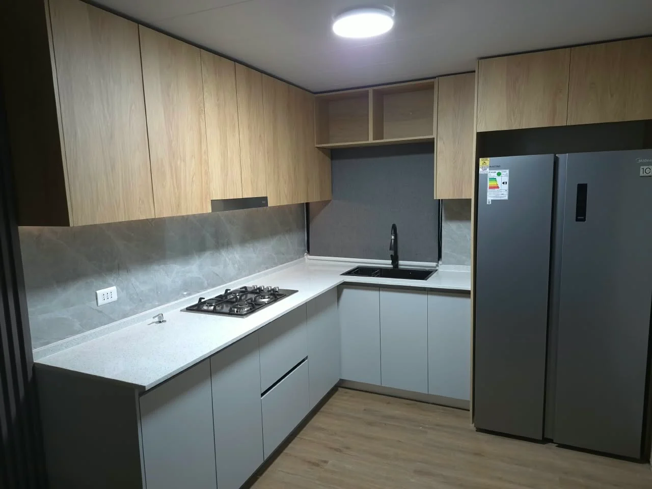 Cocina en L con muebles claros y cubierta blanca